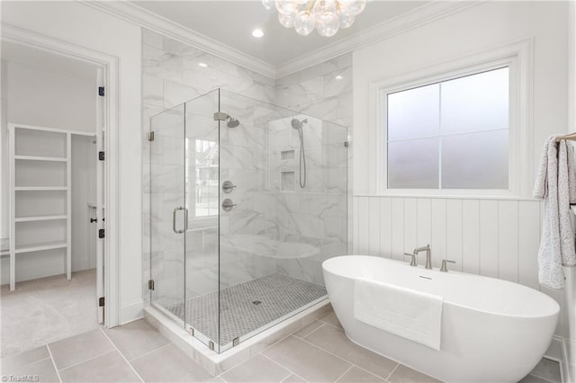 full bathroom with a marble finish shower, ornamental molding, a walk in closet, a freestanding bath, and a chandelier