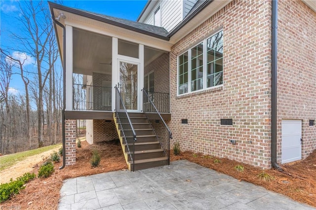 doorway to property with crawl space, a patio area, and brick siding