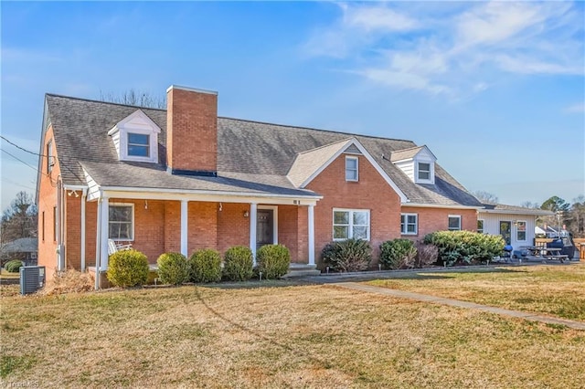 view of front of house featuring brick siding, a chimney, and a front yard