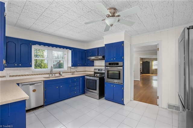 kitchen featuring under cabinet range hood, decorative backsplash, stainless steel appliances, and a sink