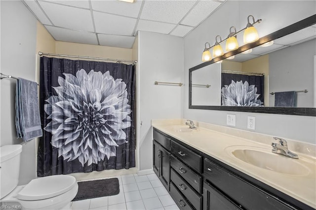 bathroom featuring double vanity, a sink, a paneled ceiling, tile patterned floors, and toilet