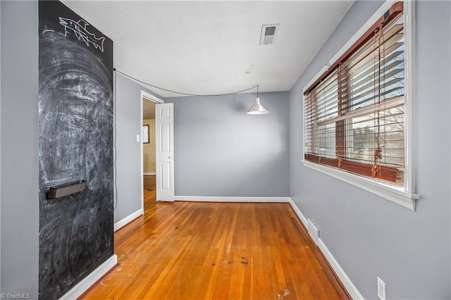 unfurnished room with visible vents, baseboards, and wood-type flooring