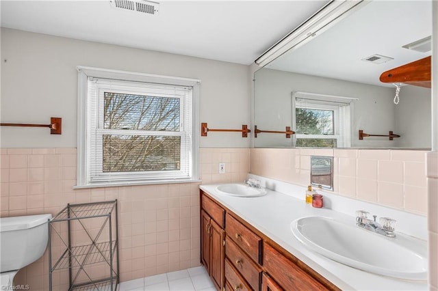 full bathroom with a sink, visible vents, and tile walls