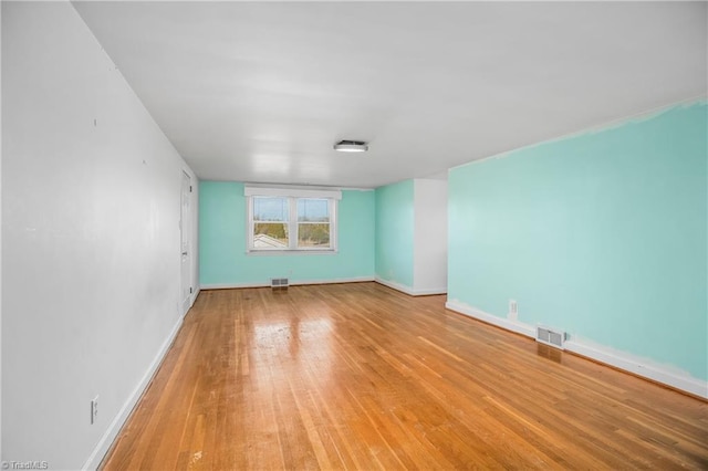 unfurnished room featuring visible vents, baseboards, and wood finished floors