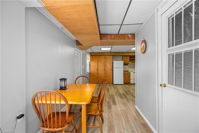 dining room with a drop ceiling, light wood-style floors, and a heating unit