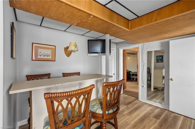 dining room featuring wood finished floors and a drop ceiling