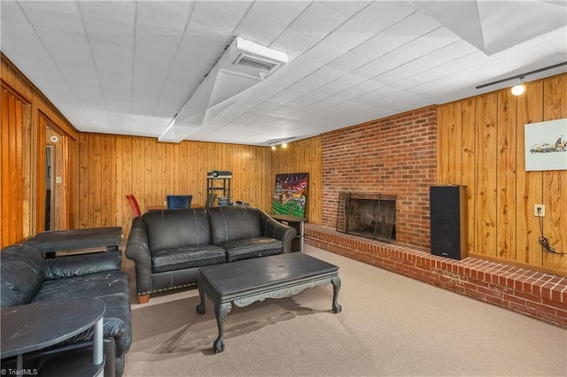 carpeted living room with visible vents, wood walls, and a brick fireplace