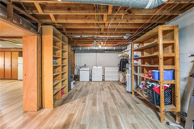 unfinished below grade area with washer and dryer, concrete block wall, wood finished floors, and water heater