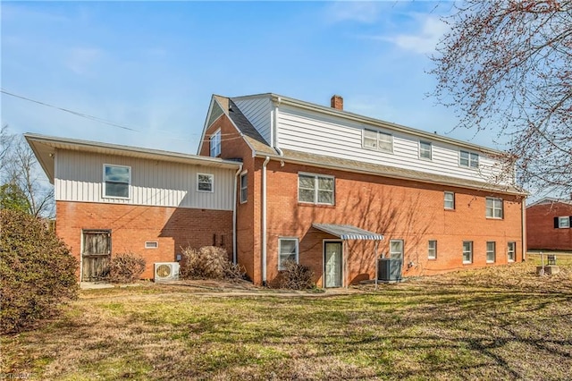 rear view of property with a lawn, brick siding, central AC, and a chimney