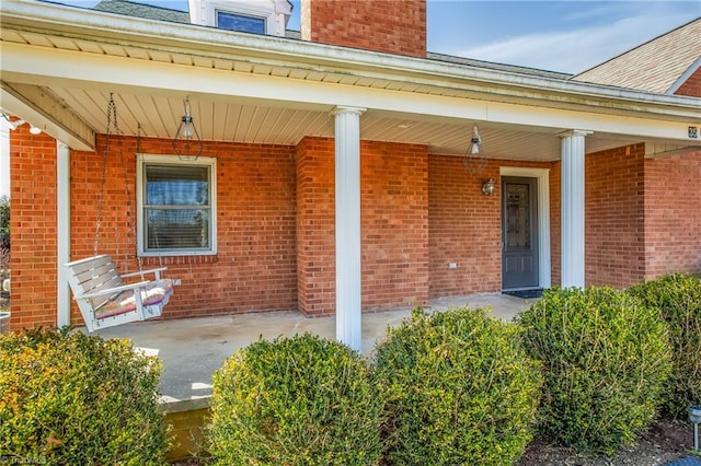 property entrance with brick siding and a porch