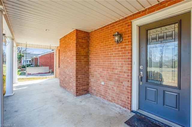 doorway to property with brick siding and a porch