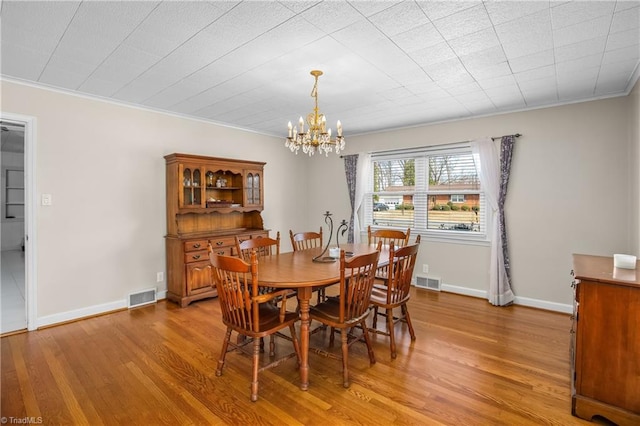 dining area featuring visible vents, crown molding, light wood-type flooring, and baseboards