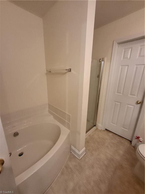 bathroom with toilet, tile patterned floors, a shower stall, and a bath