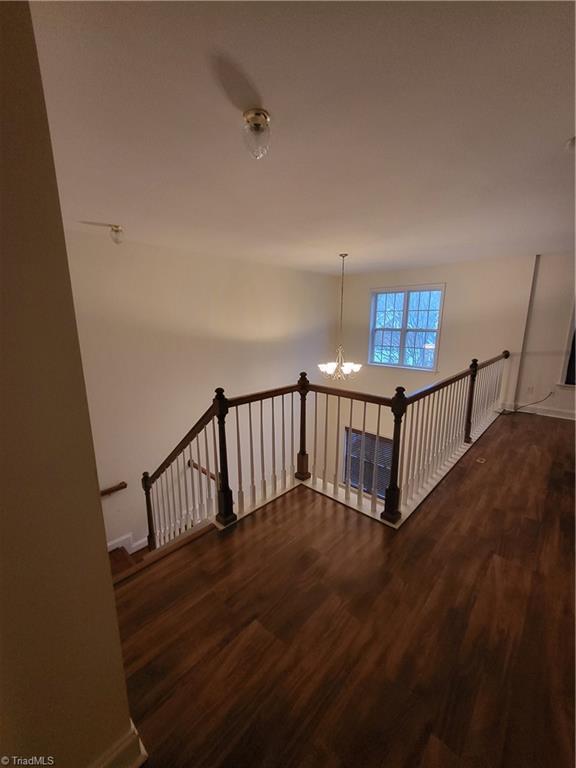 stairs with baseboards, wood finished floors, and a notable chandelier