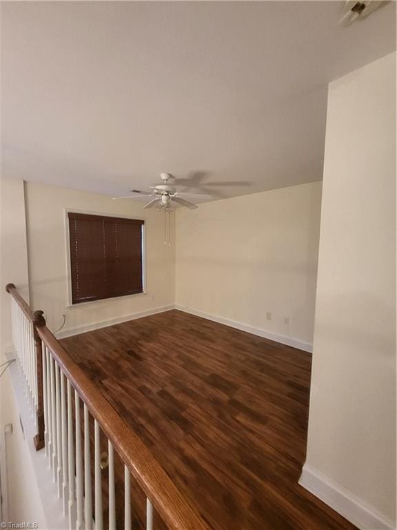 spare room with baseboards, ceiling fan, and wood finished floors