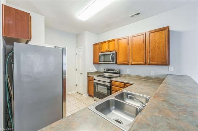 kitchen featuring light tile patterned floors, appliances with stainless steel finishes, and sink