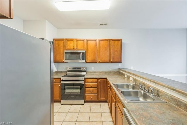 kitchen featuring appliances with stainless steel finishes, sink, and light tile patterned floors