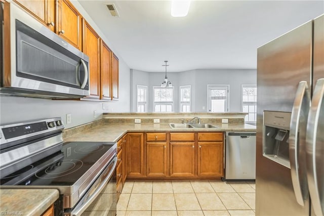 kitchen featuring a wealth of natural light, sink, appliances with stainless steel finishes, and decorative light fixtures