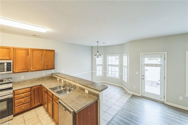 kitchen with a notable chandelier, sink, appliances with stainless steel finishes, and kitchen peninsula