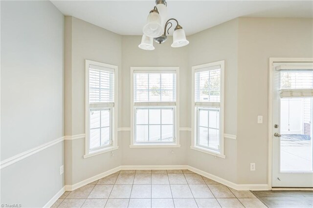 unfurnished dining area featuring a healthy amount of sunlight, light tile patterned floors, and a chandelier