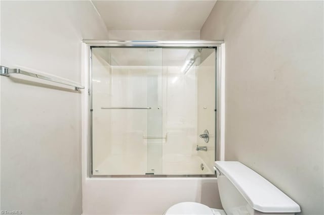 bathroom with combined bath / shower with glass door and toilet