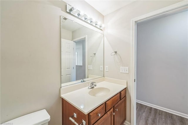 bathroom with toilet, hardwood / wood-style flooring, and vanity