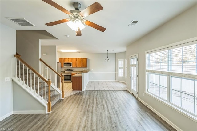 living room featuring wood-type flooring and ceiling fan with notable chandelier