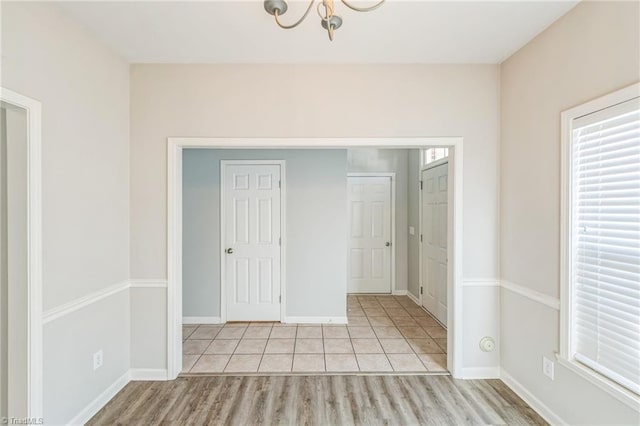 unfurnished bedroom featuring a closet, light hardwood / wood-style floors, and a notable chandelier