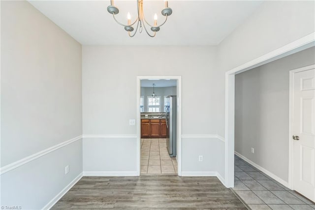 unfurnished dining area with an inviting chandelier and light hardwood / wood-style flooring