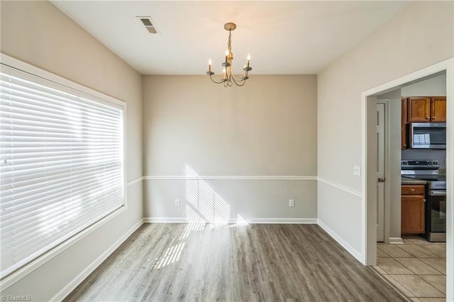 unfurnished dining area with a chandelier and light wood-type flooring