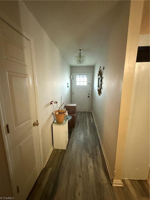 doorway to outside with dark wood-type flooring and a textured ceiling