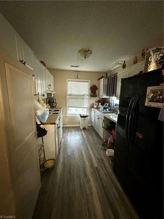 kitchen with a textured ceiling, black fridge with ice dispenser, white cabinets, and dark hardwood / wood-style floors