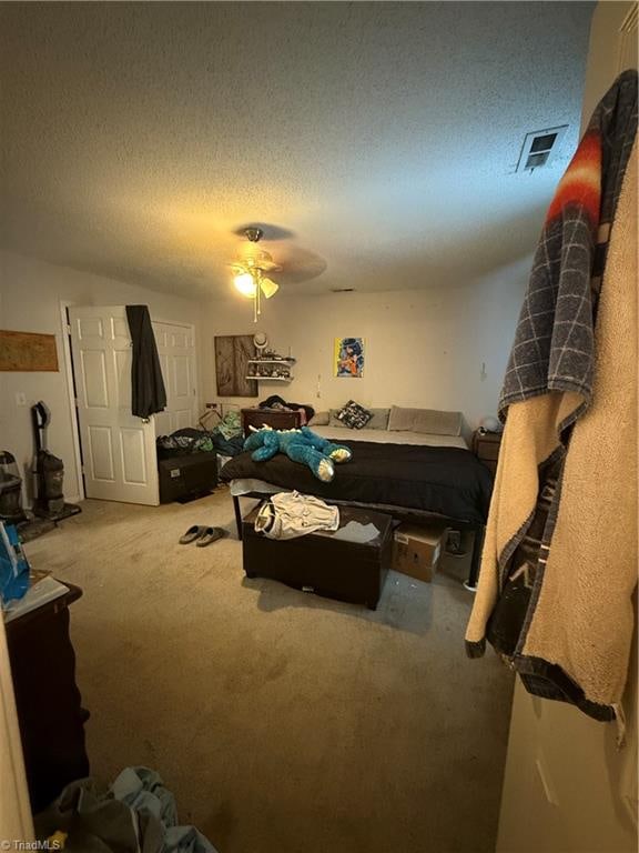 carpeted bedroom with ceiling fan and a textured ceiling