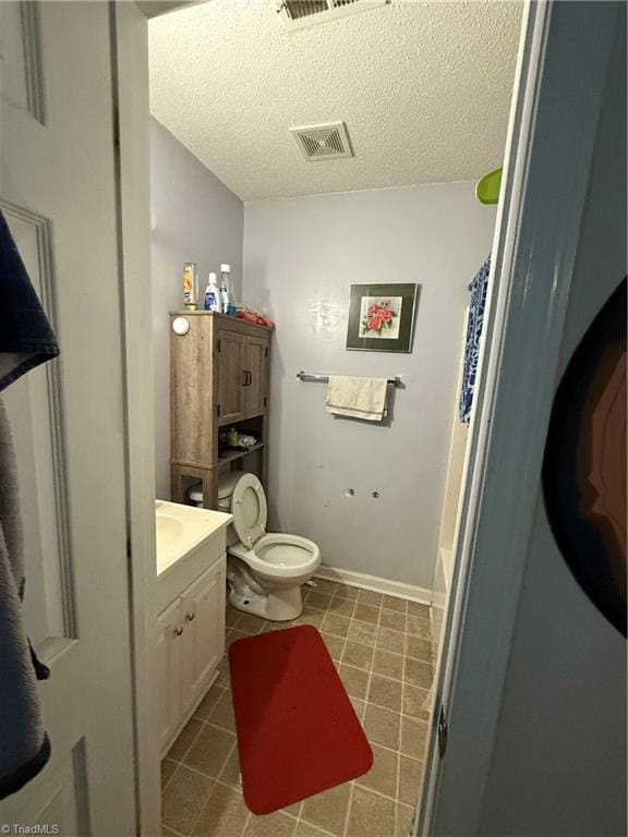 bathroom featuring vanity, a textured ceiling, and toilet