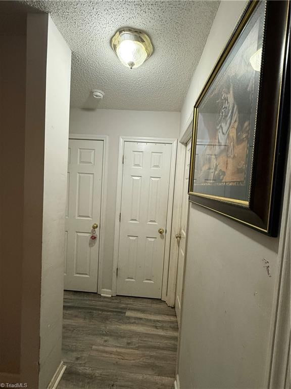 hall featuring a textured ceiling and dark hardwood / wood-style floors