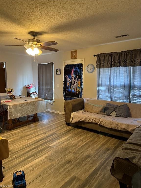 living room featuring hardwood / wood-style flooring, ceiling fan, and a textured ceiling