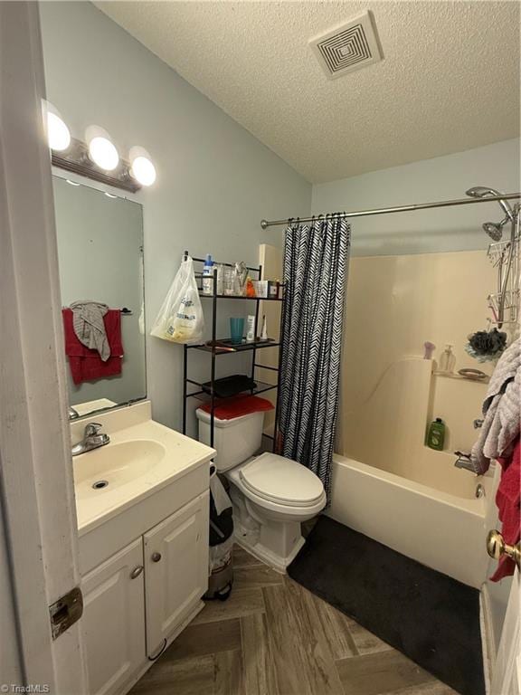 full bathroom featuring parquet floors, a textured ceiling, vanity, shower / tub combo with curtain, and toilet