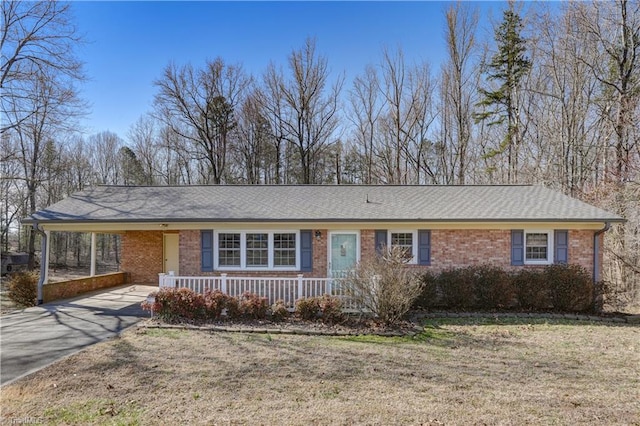 ranch-style home featuring brick siding, covered porch, an attached carport, driveway, and a front lawn