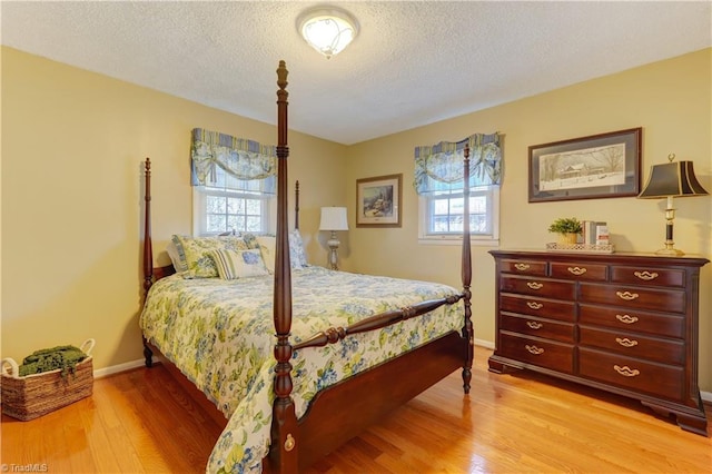 bedroom featuring a textured ceiling, light wood-type flooring, and baseboards