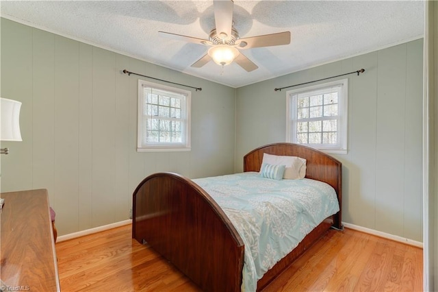 bedroom with baseboards, a textured ceiling, a ceiling fan, and wood finished floors