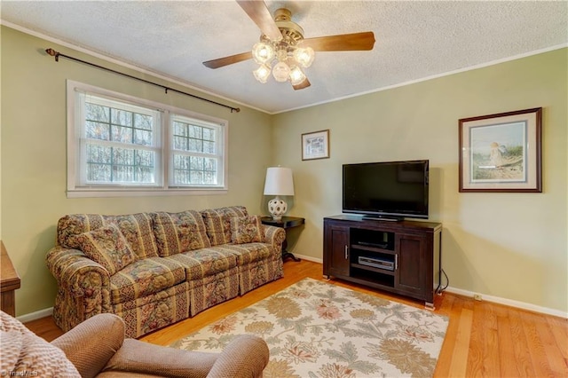 living room with a textured ceiling, baseboards, wood finished floors, and crown molding