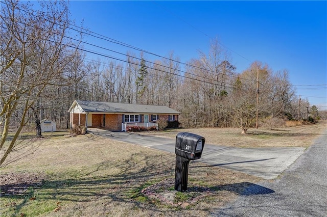 view of front facade featuring concrete driveway, brick siding, and a front yard