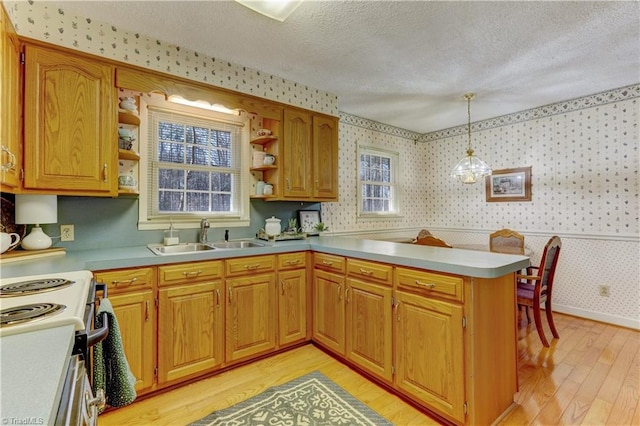 kitchen with a textured ceiling, a peninsula, a sink, open shelves, and wallpapered walls