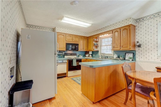 kitchen with black microwave, electric range oven, and wallpapered walls