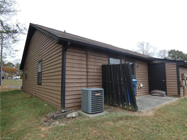 view of side of property featuring central air condition unit and a yard