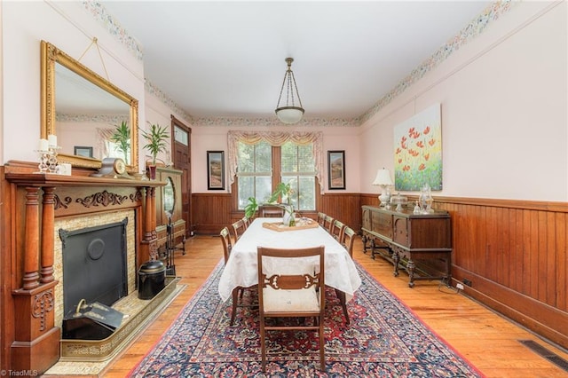 dining room featuring hardwood / wood-style floors, a fireplace, and wooden walls