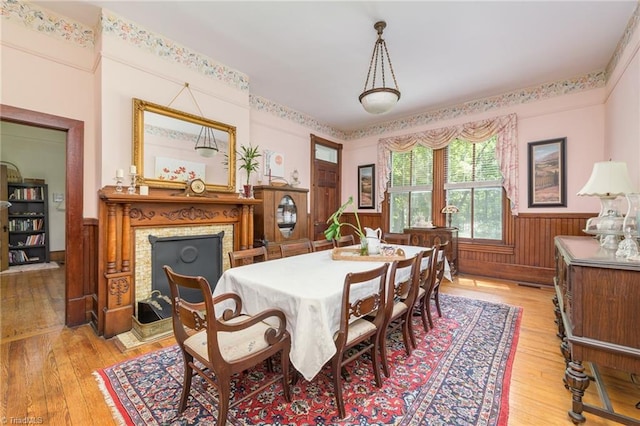 dining area with a high end fireplace, light hardwood / wood-style flooring, and wood walls