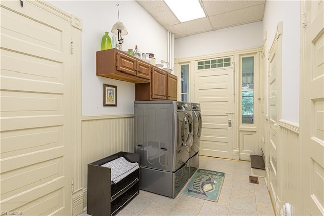 washroom with light tile patterned floors, cabinets, and washing machine and dryer