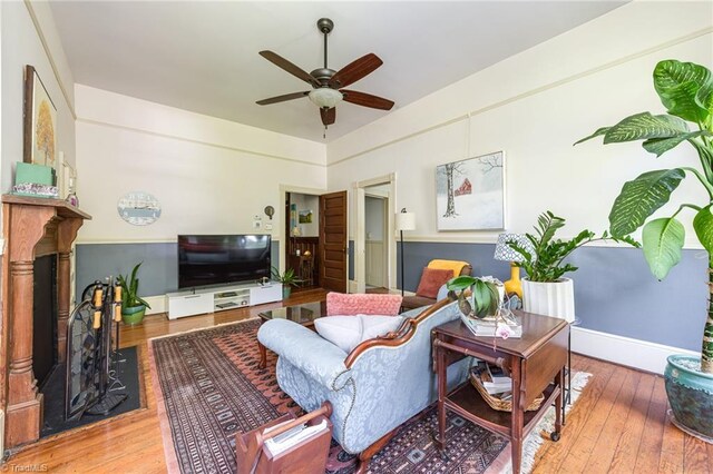 living room with hardwood / wood-style floors, ceiling fan, and a fireplace