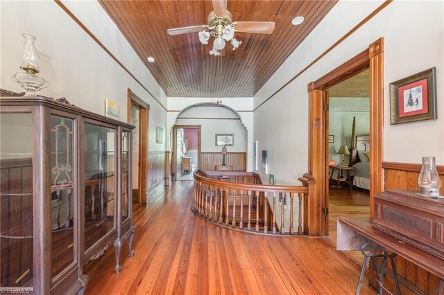 hall with wood-type flooring, wooden ceiling, and wooden walls